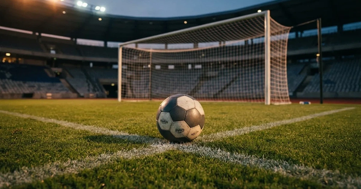 Ein Fußball liegt im Strafraum direkt vor dem Tor mit Netz, im Hintergrund leere Ränge bei Dämmerung.