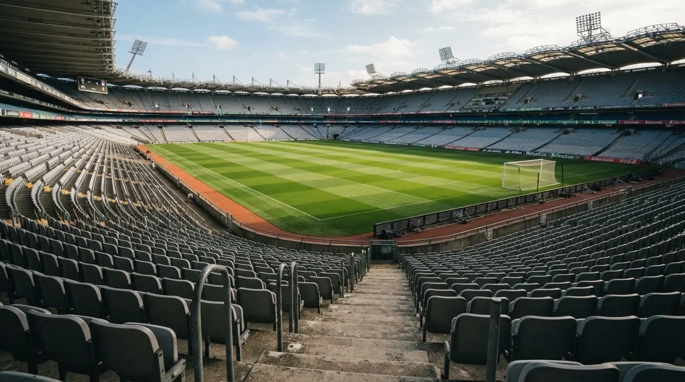 Ein leeres Fußballstadion bei Tageslicht von der Tribüne aus gesehen, der Rasen zeigt gleichmäßige Mähstreifen.