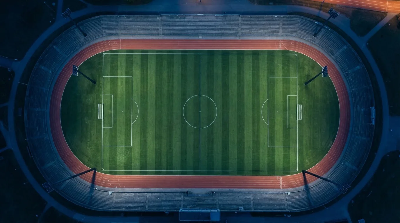 Ein Fußballplatz am Abend aus der Vogelperspektive, Flutlichtmasten ausgeschaltet, die Rasenlinien deutlich sichtbar.