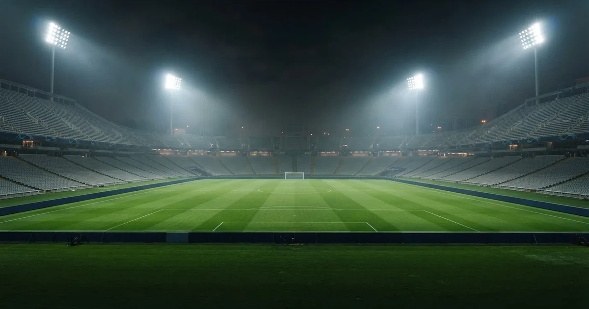 Ein leeres Stadion unter Flutlicht aus großer Entfernung gesehen, Dunst liegt über dem Rasen, die Tribünen sind nur als Lichtpunkte erkennbar.